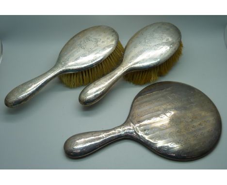 Two silver backed brushes and a hand mirror 