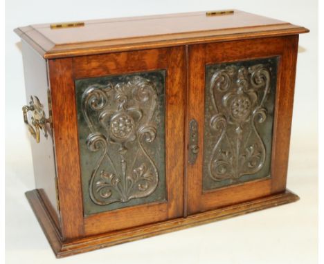 Early C20th oak desktop smoker's cabinet, with two hinged doors inset with Art Nouveau metal panels, interior fitted with pip