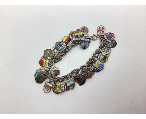 A Vintage Enamel Shield Souvenir Charm Bracelet, suspending numerous assorted shield pendants.