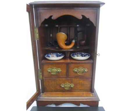 AN EDWARDIAN OAK SMOKERS CABINET With bevelled glass door, the interior fitted with shelf and three drawers; together with an