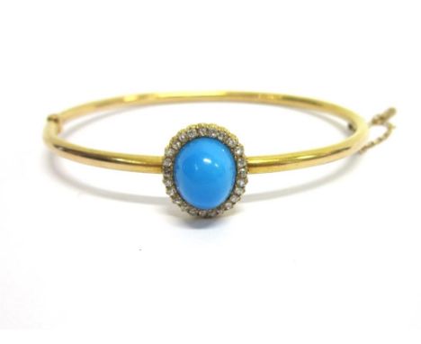 A LATE VICTORIAN TURQUOISE AND DIAMOND CLUSTER HINGED BANGLE the oval cabochon of approximately 11x9.5mm diameter, enclosed b