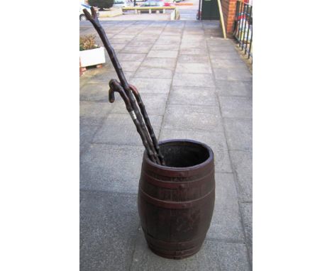 A COOPERED OAK IRON BOUND OVAL BARREL STICK STAND 61cm high; together with three walking sticks including a white metal bound