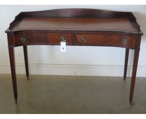 A late Victorian/Edwardian mahogany Carlton house style inverted breakfront writing table fitted with a tooled leather writin