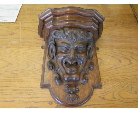 A carved oak wall clock bracket in the form of pan - 37 cm x 33 cm 