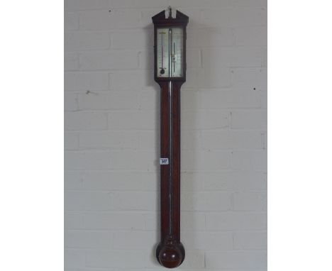 A Georgian mahogany stick barometer with a broken arch pediment over a silvered dial reading very dry to stormy with thermome