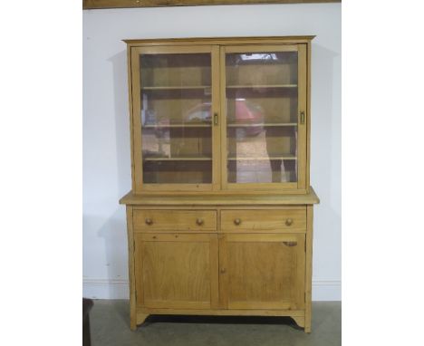 A pine dresser with two glazed sliding doors, shelves to interior over base of two short drawers above two doors raised on br