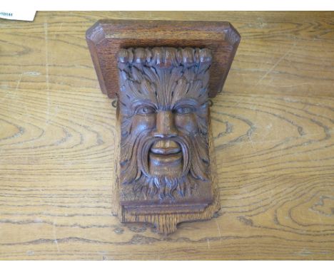 A carved oak wall clock bracket in the form of the Green Man - 26 cm x 23 cm 