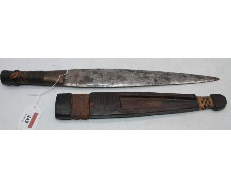 A North African dagger, having a 28cm flattened leaf shaped edged blade, with hide bound handle, in further hide bound sheath