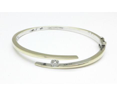 A white metal and diamond bangle, approximately 0.40 carat diamond weight, 18.6g