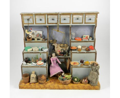 Miniature painted wooden shop and contents, French circa 1910, the pale blue and gold painted shop with six labelled draw com