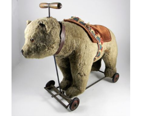 A Steiff Teddy Bear on wheels, circa 1930, light brown mohair bear with glass eyes, stitched nose, mouth and claws, with ring