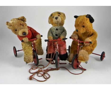 Three Chiltern Bears on Trikes, circa 1960, all with orange plastic eyes, moulded plastic noses and riding re metal trikes wi