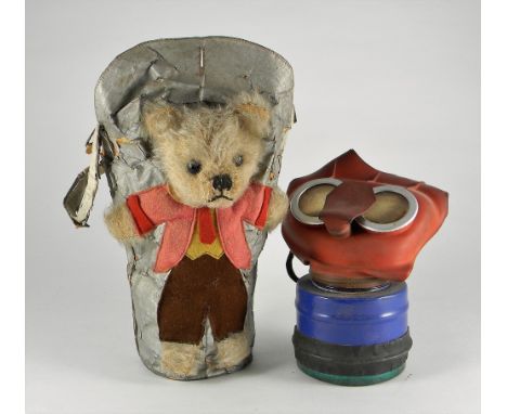 A very rare British child’s Teddy Bear gas mask holder, 1938-45, the silver covered fabric holder with dressed Teddy Bear wit