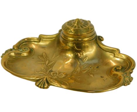 A Victorian brass inkstand, of scrolling form embossed with flowers and beads, the hinged inkwell enclosing a ceramic liner, 