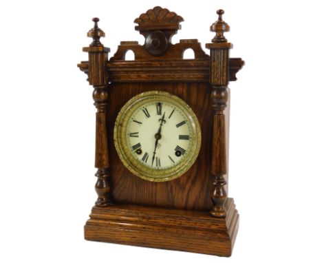 A late 19thC oak cased mantel clock, the circular cream enamel dial bearing Roman numerals, movement by The Ansonia Clock Com
