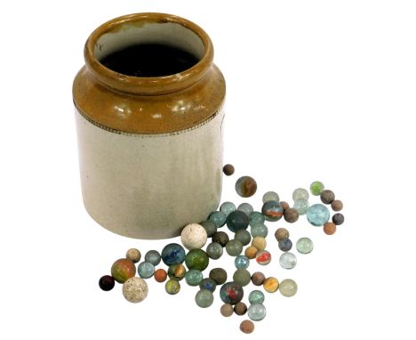 A stoneware jar containing various marbles, 19cm high. 