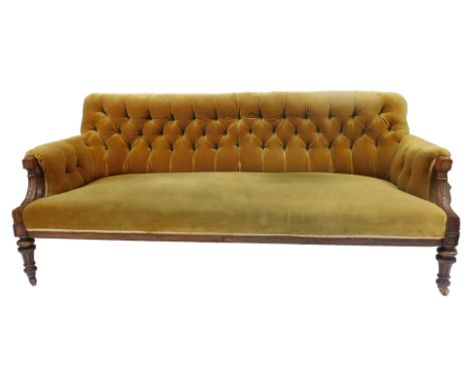 A 19thC walnut framed sofa, upholstered in gold coloured draylon fabric with a buttoned back, carved arms with leaf decoratio