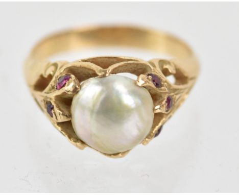 A pearl and ruby yellow metal ring, the central pearl in a claw shaped, the pierced and scroll designs shoulders set with fiv