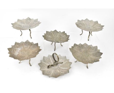 A set of six Oriental filigree white metal dishes, possibly Persian, the dishes in a floral form with foliate scrolls, fittin