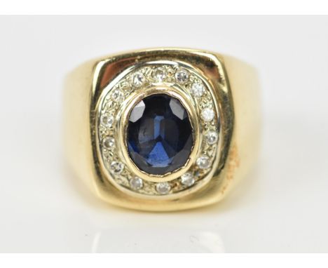 A yellow metal, diamond and blue sapphire gentlemen's signet style dress ring, with central oval cut sapphire in rub over set