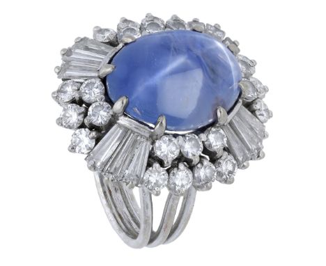 A star sapphire and diamond cluster ring, the sapphire cabochon set within a cluster surround of tapered baguette and brillia