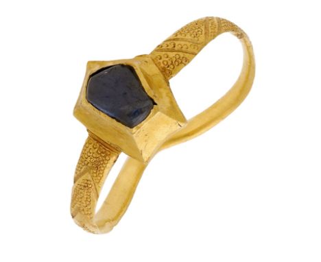 An early 14th century gold and sapphire ring, the flat band centred with a  pentagonal cabochon sapphire mounted within a rai