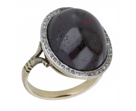 A garnet and diamond dress ring, the garnet cabochon in a closed back setting within a surround of rose-cut diamonds, ring si