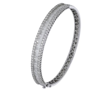 A diamond bangle, set to the front with a row of baguette-cut diamonds with a border of brilliant-cut diamonds to either side