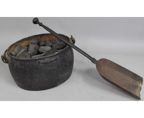 A Vintage Cast Iron Cooking Pot Containing Anthracite Together with a Cast Iron Fire Shovel 