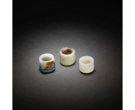 THREE JADE THUMB RINGS18th/19th centuryOne ring carved in low relief around the exterior with archaistic C-scrolls, the stone