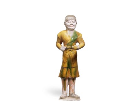 A LARGE SANCAI-GLAZED POTTERY FIGURE OF A GROOMTang DynastyThe tall figure modelled standing, with muscular arms and fists cl