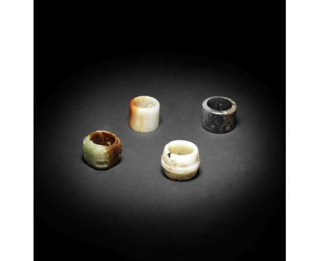 FOUR JADE THUMB RINGS17th/19th centuryComprising a pale green and russet jade thumb ring, 17th/18th century, carved with four
