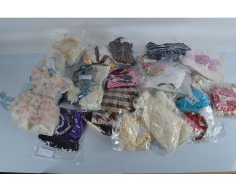 A quantity of dolls dresses and outfits, various sizes including a crimson skirt with cream blouse, large check dress and oth