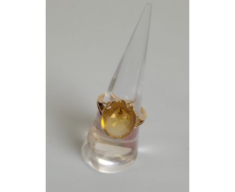 A large early 20th Century citrine dress ring, the oval cabochon topped citrine with faceted pavilion in a crown claw setting