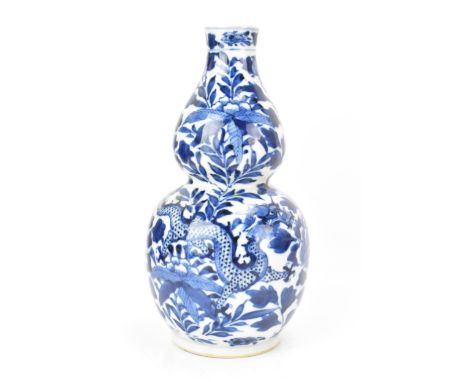 A Chinese late Qing dynasty blue and white double gourd vase, late 19th century, decorated with a four claw dragon amongst fo