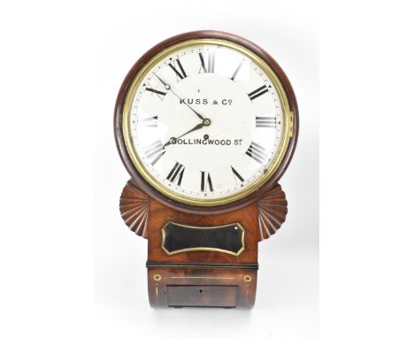 A Regency mahogany 12" drop dial clock, the case with carved fan ears, glazed pendulum aperture and curved base inlaid with b