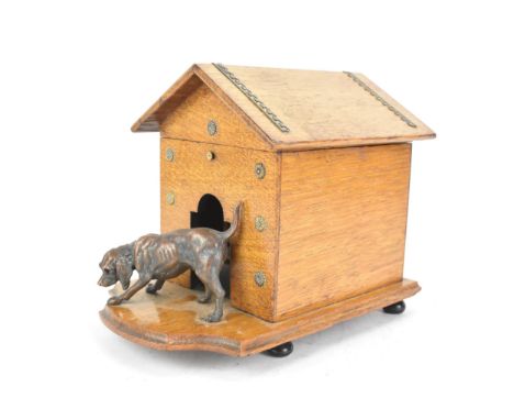 An early 20th century oak novelty cigar and music box, in the form of a kennel with patinated metal dog to the front, the hin