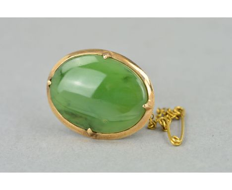 A JADE BROOCH, of oval outline to the plain surround with safety clasp, stamped 9ct, length 27mm, weight 6.3 grams