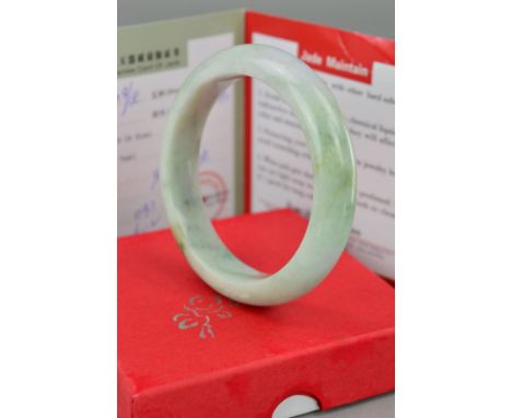 A MODERN JADE (JADITE) SOLID SLAVE BANGLE, pale green in colour measuring approximately 60.0mm inner diameter, outer 75.0mm i