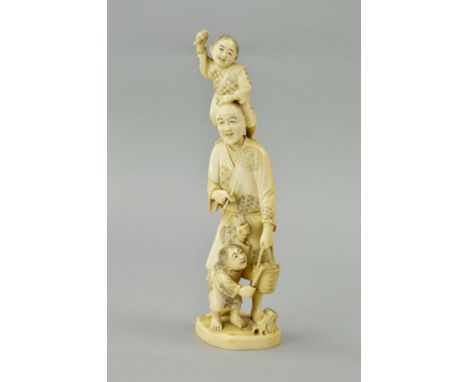 A LATE 19TH CENTURY JAPANESE IVORY OKIMONO, carved with a young boy holding a stick standing on a man's shoulders, the man wi