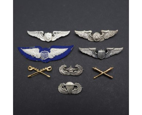 A collection of insignia including a cloth patch with padded wings against a blue ground, metal badges to include airborne ju