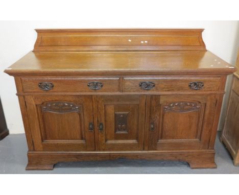 Art Nouveau design oak sideboard with foliate moulded panels to the three cupboard doors, below two frieze drawers with styli