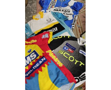 A TRAY OF ASSORTED VINTAGE CYCLING JERSEYS TO INCLUDE NORTHERN IRELAND MILK RACE POINT LEADER JERSEY TOGETHER WITH A HELMET