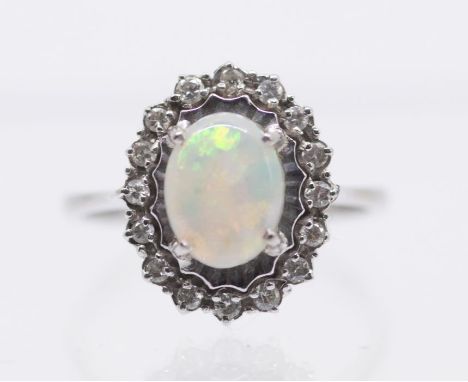 An opal and diamond cluster ring in 18ct white gold. Set with an opal cabochon with green to blue play of colour. Gross weigh