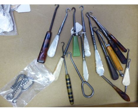 TWENTY VARIOUSLY HANDLED BUTTON HOOKS, TO INCLUDE: ONE FOLDING INTO A SPRING LOADED HANDLE, ANOTHER FOLDING INTO A STEEL HAND