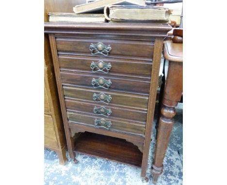 AN EADWARDIAN MAHOGANY MUSIC CABINET WITH SIX DRAWERS ABOVE AN OPEN SHELF