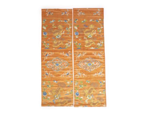   A pair of Chinese peach silk embroidered hangings, 19th centuryeach embroidered with Buddhist lions playing with a brocaded