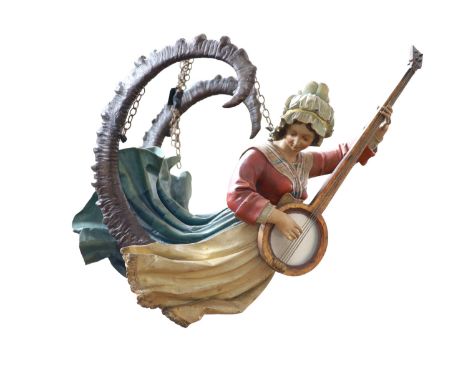   A late 19th century carved and painted wood Lusterweibchenmodelled as a woman playing a banjo with mountain goat horns curv