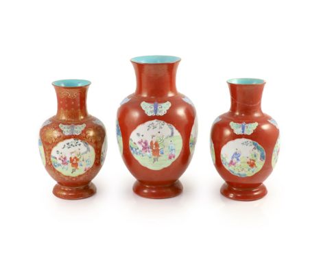   A set of three Chinese coral ground ‘boys’ vases, Jiaqing period (1796-1820),each painted in famille rose enamels to shaped