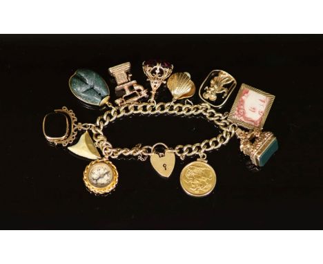   A 1970's 9ct. gold charm bracelet,hung with ten assorted charms, including old telephone, a mounted 1882 sovereign and comp